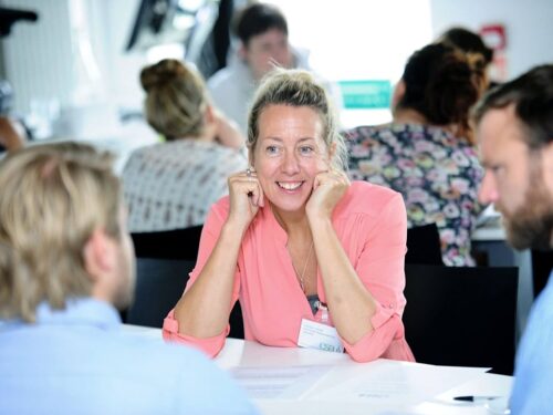 A lady having a discussion with 2 peers at work.